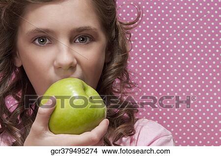 Close-up of a girl eating a green apple View Large Photo Image Picture - Close-up of a girl eating a green apple. Fotosearch
