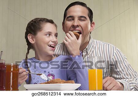 Close-up of a girl feeding toast to her father View Large Photo Image Picture - Close-up of a girl feeding toast to her father. Fotosearch