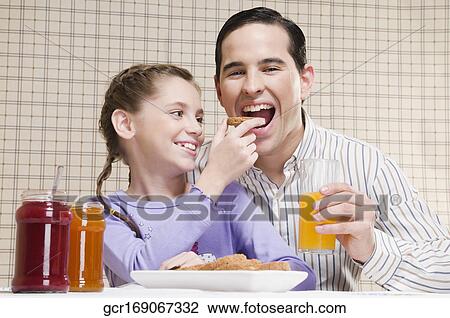Close-up of a girl feeding toast to her father View Large Photo Image Stock Image - Close-up of a girl feeding toast to her father. Fotosearch