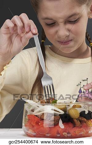 Close-up of a girl frowning at a bowl of salad View Large Photo Image Picture - Close-up of a girl frowning at a bowl of salad. Fotosearch