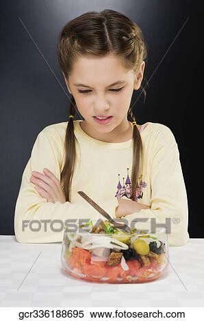 Close-up of a girl frowning at a bowl of salad View Large Photo Image Stock Photography - Close-up of a girl frowning at a bowl of salad. Fotosearch