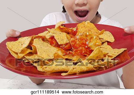 Picture - Close-up of a girl holding a platter of nachos. Fotosearch