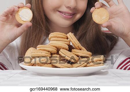 Close-up of a girl holding an open cream cookie View Large Photo Image Stock Photo - Close-up of a girl holding an open cream cookie. Fotosearch