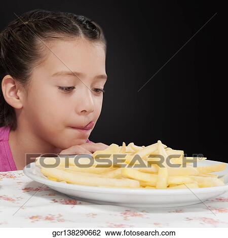 Close-up of a girl looking at French fries View Large Photo Image Stock Image - Close-up of a girl looking at French fries. Fotosearch