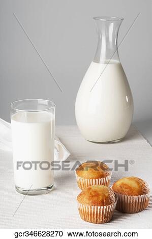 Stock Image - Close-up of a glass of milk with cupcakes. Fotosearch
