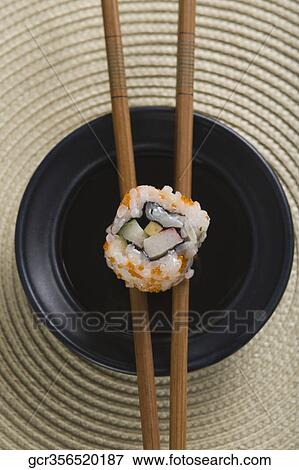 Close-up of a maki sushi with chopsticks on a bowl View Large Photo Image Stock Photo - Close-up of a maki sushi with chopsticks on a bowl. Fotosearch