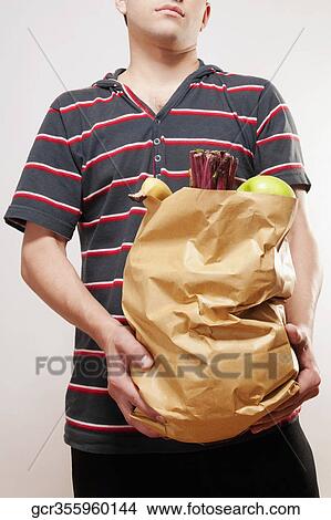 Close-up of a man holding a bag of fruits and vegetables View Large Photo Image Picture - Close-up of a man holding a bag of fruits and vegetables. Fotosearch