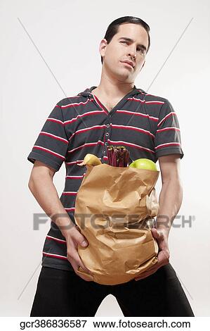 Close-up of a man holding a bag of fruits and vegetables View Large Photo Image Stock Photo - Close-up of a man holding a bag of fruits and vegetables. Fotosearch
