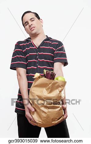 Close-up of a man holding a bag of fruits and vegetables View Large Photo Image Stock Photo - Close-up of a man holding a bag of fruits and vegetables. Fotosearch