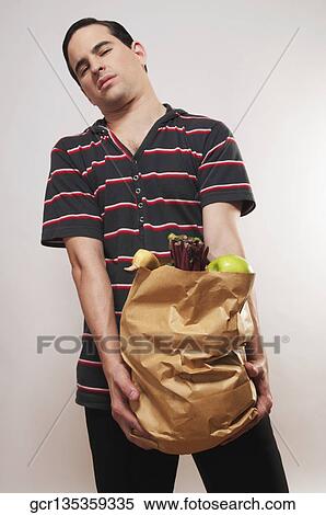 Stock Photography - Close-up of a man holding a bag of vegetables. Fotosearch