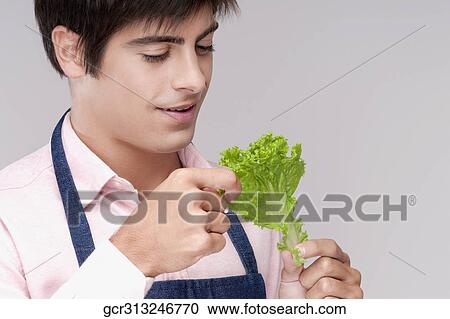 Stock Image - Close-up of a man holding a lettuce leaf. Fotosearch
