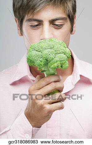 Close-up of a man smelling a broccoli View Large Photo Image Stock Image - Close-up of a man smelling a broccoli. Fotosearch