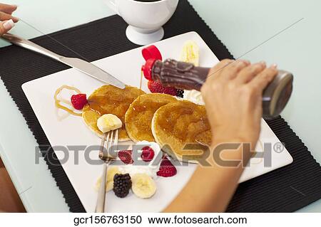 Close-up of a person pouring syrup on pancakes View Large Photo Image Stock Image - Close-up of a person pouring syrup on pancakes. Fotosearch