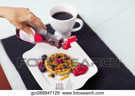 Close-up of a person pouring syrup on waffles View Large Photo Image Stock Photo - Close-up of a person pouring syrup on waffles. Fotosearch