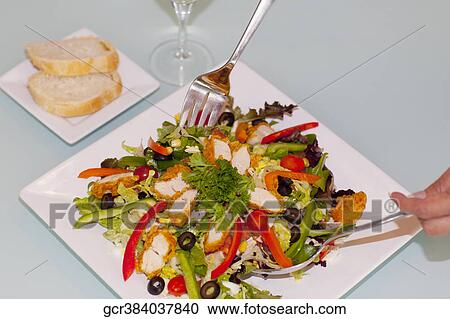 Stock Image - Close-up of a person's hand tossing salad. Fotosearch