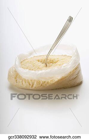 Stock Image - Close-up of a plastic bag of rice with a spoon. Fotosearch