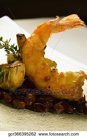 Stock Image - Close-up of a prawn fritter served on a bed of peanuts. Fotosearch