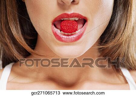 Stock Image - Close-up of a raspberry in a woman's mouth. Fotosearch
