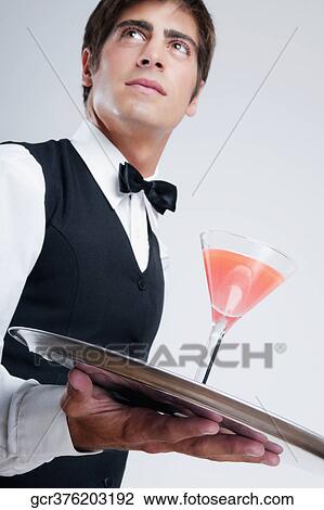Stock Image - Close-up of a waiter holding a cocktail on a tray. Fotosearch