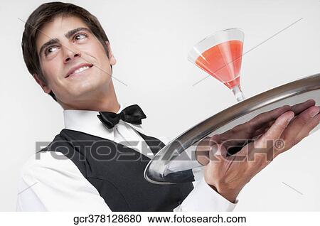 Stock Image - Close-up of a waiter holding a cocktail on a tray. Fotosearch