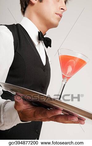 Stock Image - Close-up of a waiter holding a cocktail on a tray. Fotosearch