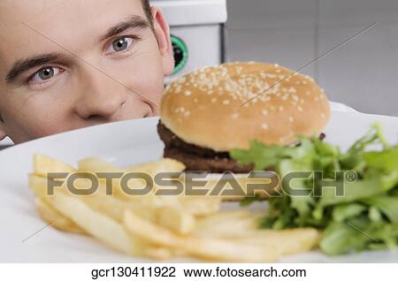 Stock Image - Close-up of a waiter looking at a burger. Fotosearch