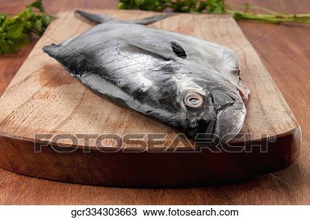 Close-up of a whole raw fish on a cutting board View Large Photo Image Stock Image - Close-up of a whole raw fish on a cutting board. Fotosearch