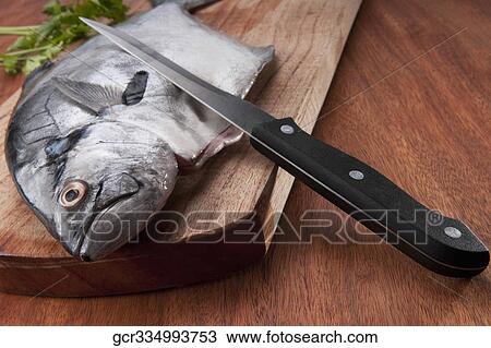 Close-up of a whole raw fish on a cutting board View Large Photo Image Stock Image - Close-up of a whole raw fish on a cutting board. Fotosearch