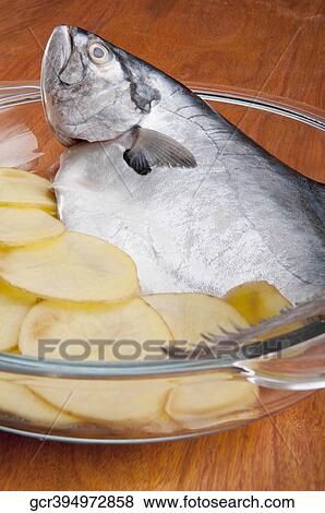 Close-up of a whole raw fish with sliced potatoes View Large Photo Image Stock Photo - Close-up of a whole raw fish with sliced potatoes. Fotosearch