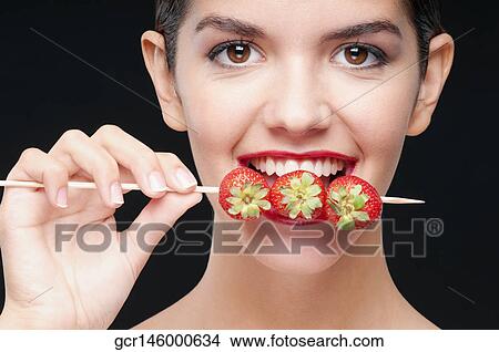 Close-up of a woman biting strawberries on a skewer View Large Photo Image Picture - Close-up of a woman biting strawberries on a skewer. Fotosearch
