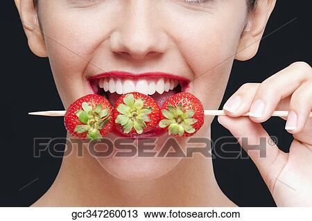 Close-up of a woman biting strawberries on a skewer View Large Photo Image Stock Image - Close-up of a woman biting strawberries on a skewer. Fotosearch