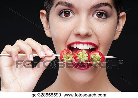 Close-up of a woman biting strawberries on a skewer View Large Photo Image Stock Photo - Close-up of a woman biting strawberries on a skewer. Fotosearch