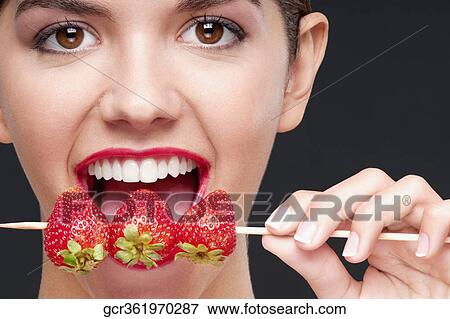 Close-up of a woman biting strawberries on a skewer View Large Photo Image Stock Photo - Close-up of a woman biting strawberries on a skewer. Fotosearch