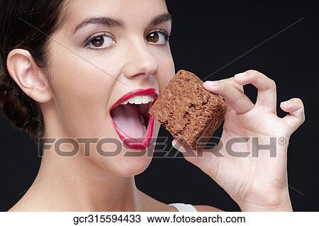 Close-up of a woman eating a brownie View Large Photo Image Stock Image - Close-up of a woman eating a brownie. Fotosearch