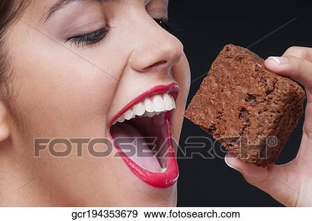 Stock Photo - Close-up of a woman eating a brownie. Fotosearch