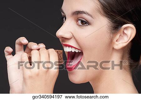 Close-up of a woman eating a brownie View Large Photo Image Stock Photo - Close-up of a woman eating a brownie. Fotosearch
