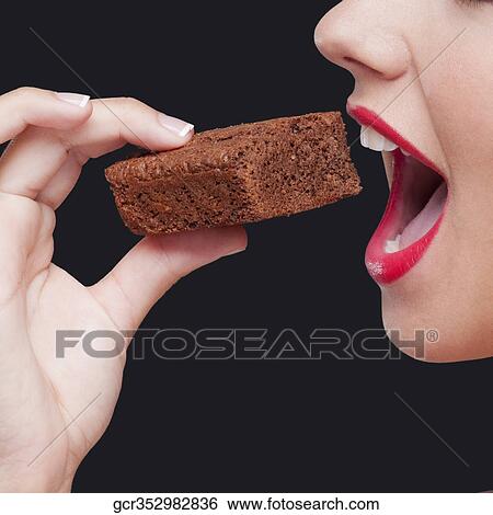 Close-up of a woman eating a brownie View Large Photo Image Stock Photograph - Close-up of a woman eating a brownie. Fotosearch