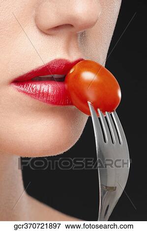 Close-up of a woman eating a cherry tomato View Large Photo Image Stock Photo - Close-up of a woman eating a cherry tomato. Fotosearch