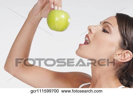 Close-up of a woman eating a granny smith apple View Large Photo Image Stock Image - Close-up of a woman eating a granny smith apple. Fotosearch