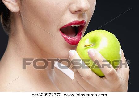Close-up of a woman eating a granny smith apple View Large Photo Image Stock Image - Close-up of a woman eating a granny smith apple. Fotosearch