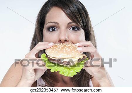 Close-up of a woman eating a hamburger View Large Photo Image Stock Photo - Close-up of a woman eating a hamburger. Fotosearch