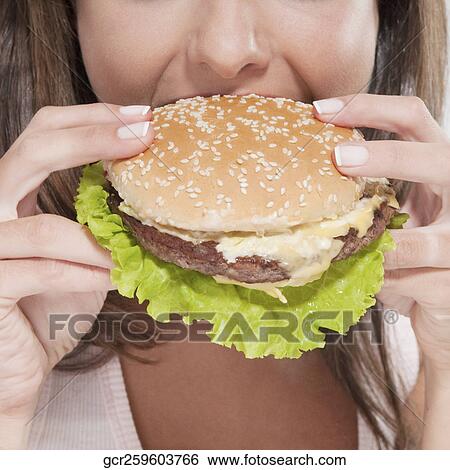 Close-up of a woman eating a hamburger View Large Photo Image Stock Photograph - Close-up of a woman eating a hamburger. Fotosearch