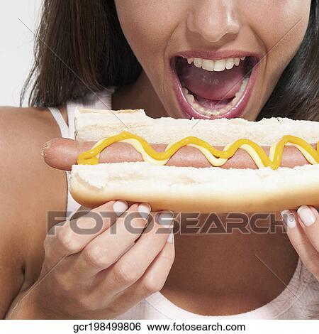 Stock Photograph - Close-up of a woman eating a hot dog. Fotosearch