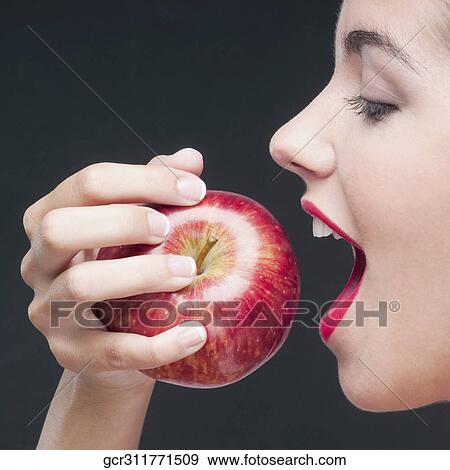 Close-up of a woman eating a red apple View Large Photo Image Stock Photo - Close-up of a woman eating a red apple. Fotosearch