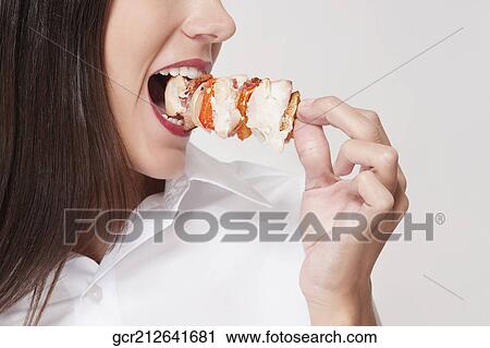 Close-up of a woman eating a shish kebab View Large Photo Image Stock Image - Close-up of a woman eating a shish kebab. Fotosearch