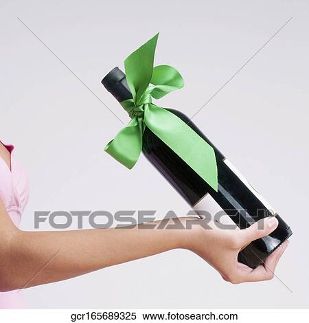 Close-up of a woman holding a bottle of wine View Large Photo Image Stock Photography - Close-up of a woman holding a bottle of wine. Fotosearch