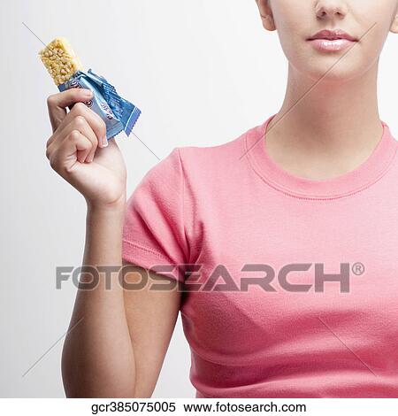Stock Photography - Close-up of a woman holding a protein bar. Fotosearch