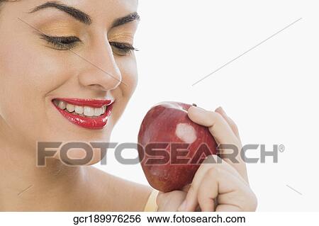 Stock Photograph - Close-up of a woman holding a red apple and smiling. Fotosearch