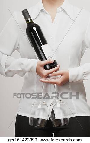 Stock Photo - Close-up of a woman holding a wine bottle with two wine glasses. Fotosearch