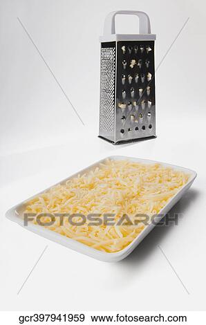 Stock Photo - Close-up of grated parmesan cheese with a cheese grater. Fotosearch